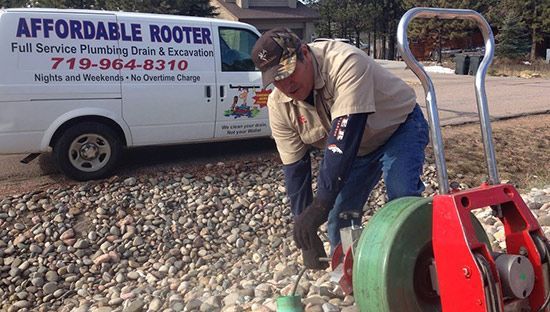 Affordable Rooter technician unloading a drain cleaning machine beside the company van